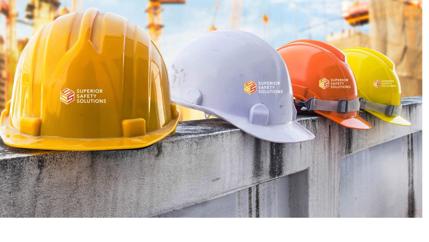 Row of Superior Safety Solutions branded hard hats on a construction ledge